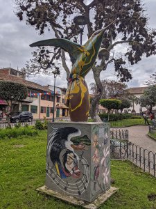 A colorful sculpture of a hummingbird on a rectangular base.